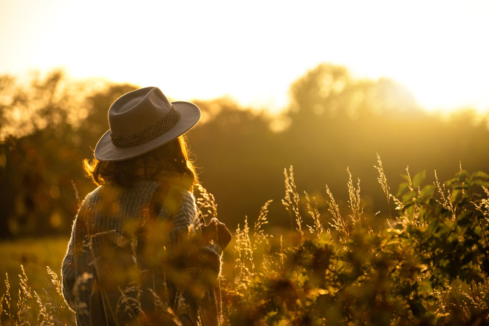 Person wearing a hat in morning sunshine outside